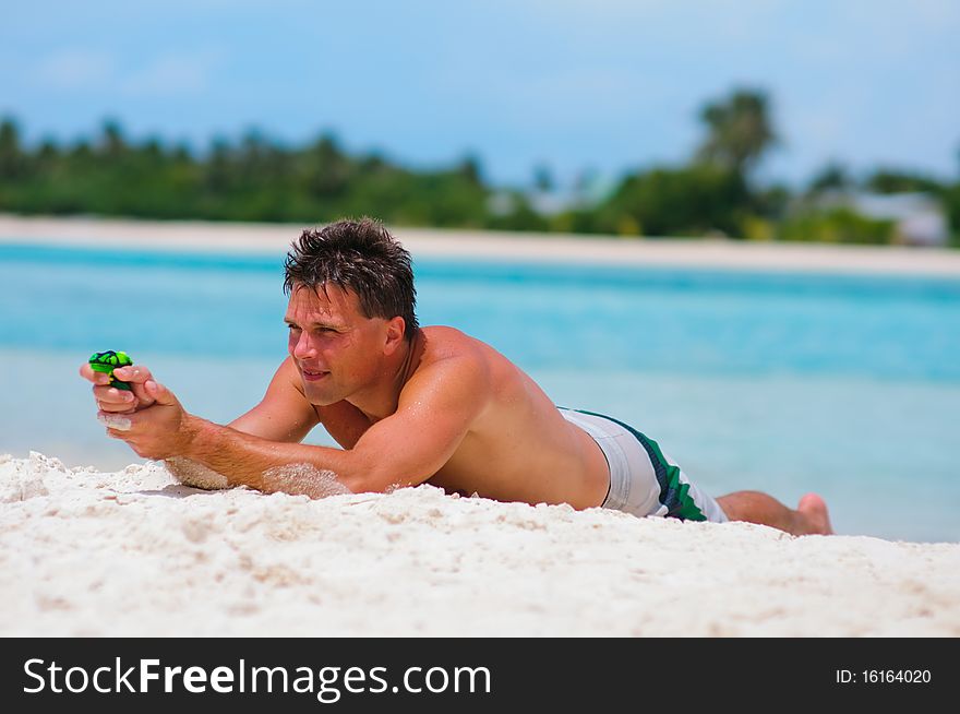 Man playing with toy water guns on exotic beach. Man playing with toy water guns on exotic beach