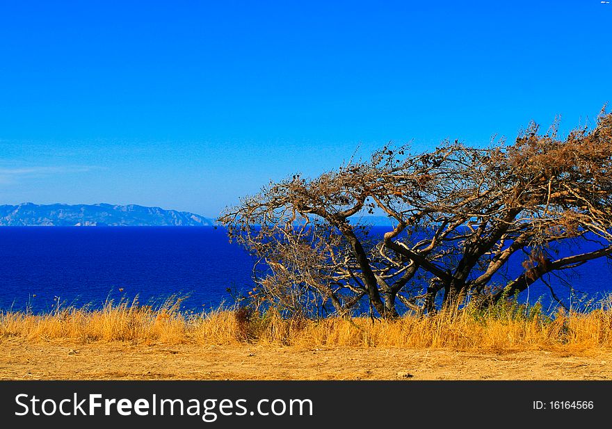 Yellow seacoast, the sea and the blue mountains in the haze. Rhodes. Greece