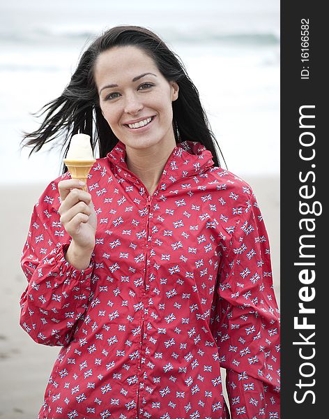 Woman wearing raincoat holding an ice cream at the beach