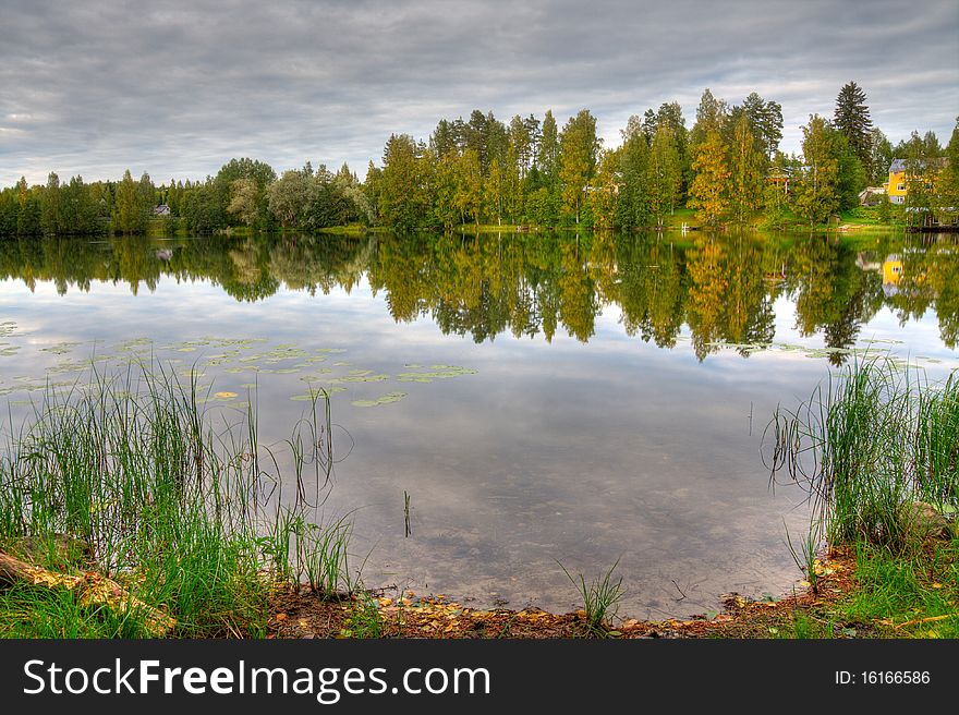 HDR photo of finnish scenery, with lake and forest and foreground of shore