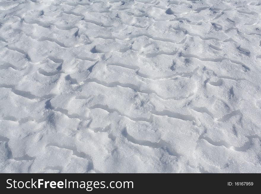 Wind blown snow drifts on frozen ice surface of a mountain lake. Wind blown snow drifts on frozen ice surface of a mountain lake