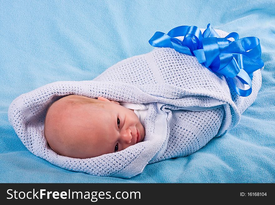 The smiling newborn fastened by the big dark blue bow