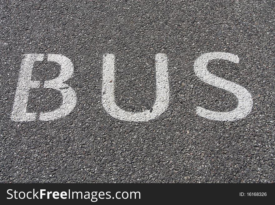 Bus sign painted on asphalt road.