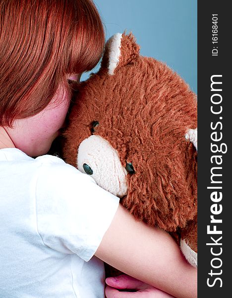 Beautiful redhead girl hugs a teddy bear.