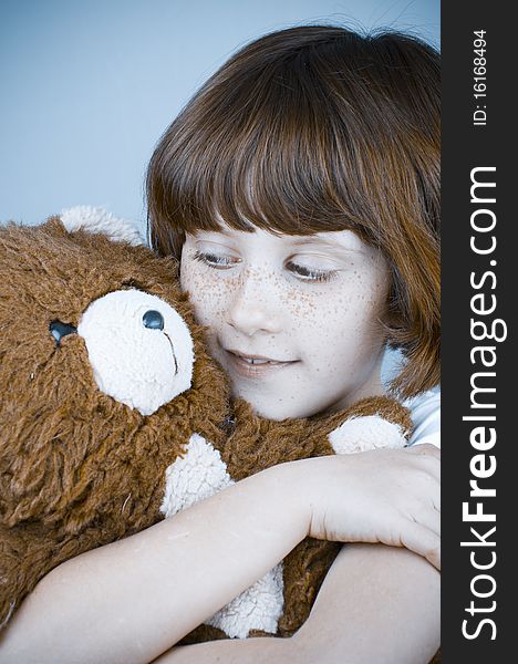 Beautiful redhead girl hugs a teddy bear.