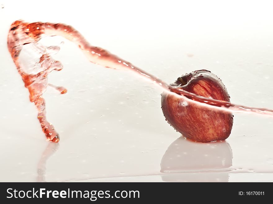 A golden red apple with a splash of water