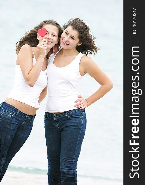 Two girls with heart-shaped candy on natural background. Two girls with heart-shaped candy on natural background