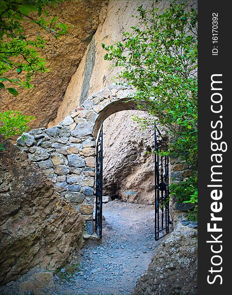 Arch with the forged gates on a mountain path