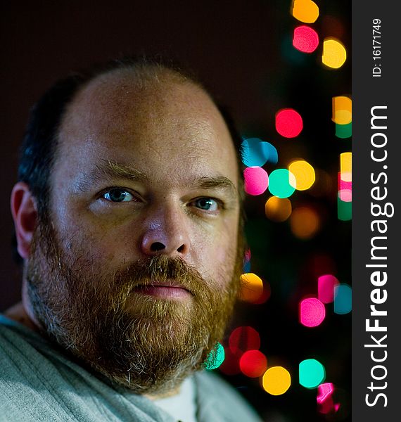 A mand looking sad in front of christmas tree. A mand looking sad in front of christmas tree