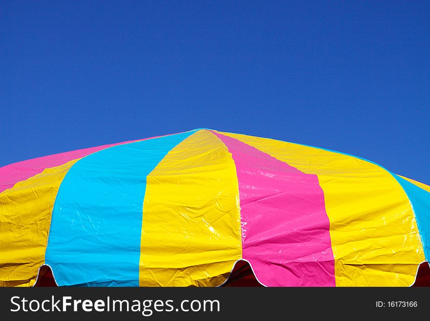 Multi-colored umbrella against a bright blue sky; with copy space for text
