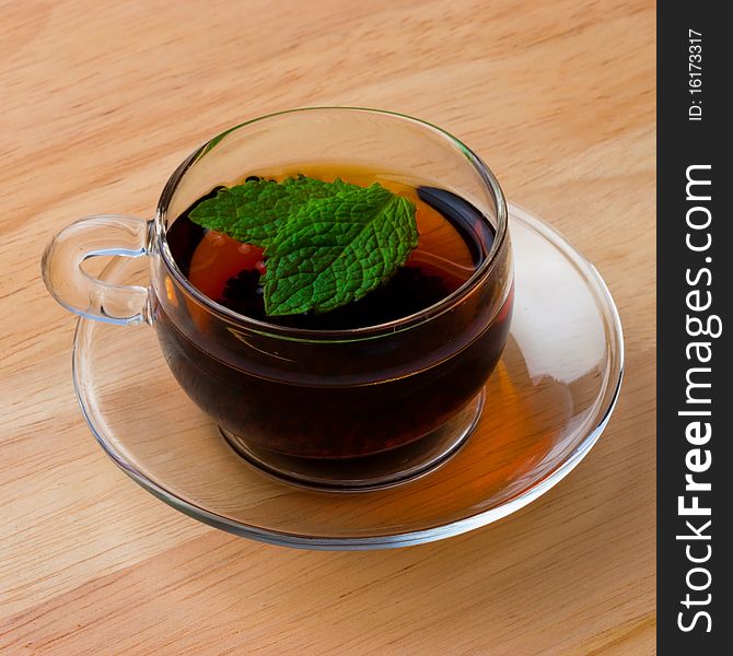 Tea in a glass cup with two mint leaves floating in it