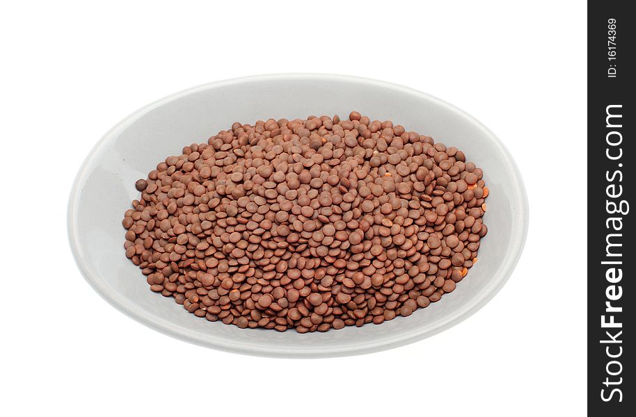 Brown uncooked lentils on plate isolated over white background