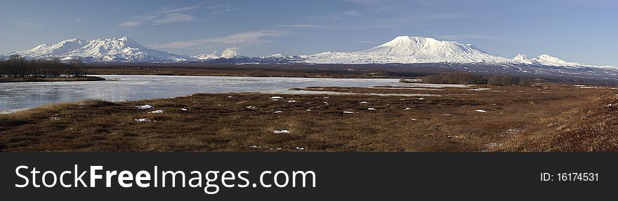 Panorama with volcanos, tundra, and the river covered by an ice. Russia. Kamchatka. Panorama with volcanos, tundra, and the river covered by an ice. Russia. Kamchatka.