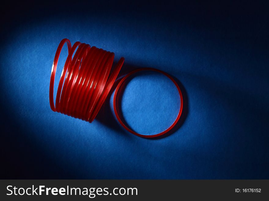 Abstract image of red bangles in dark blue background. Abstract image of red bangles in dark blue background