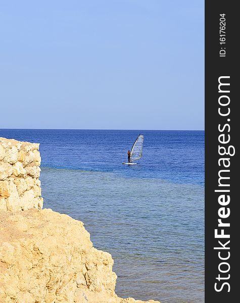 Windsurfer sailing on the sea against the blue sky. Windsurfer sailing on the sea against the blue sky