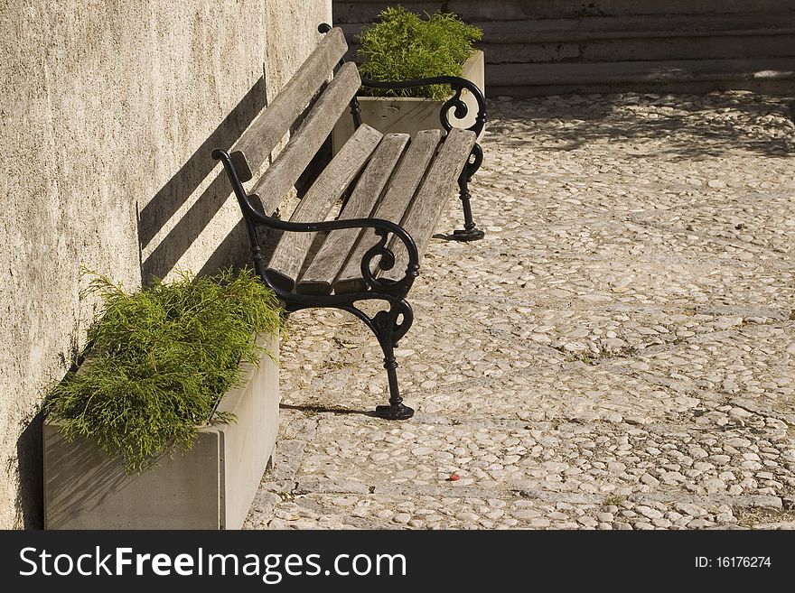 Wooden city bench with metal armrests.