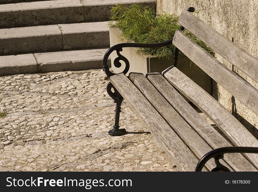 Wooden city bench with metal armrests.