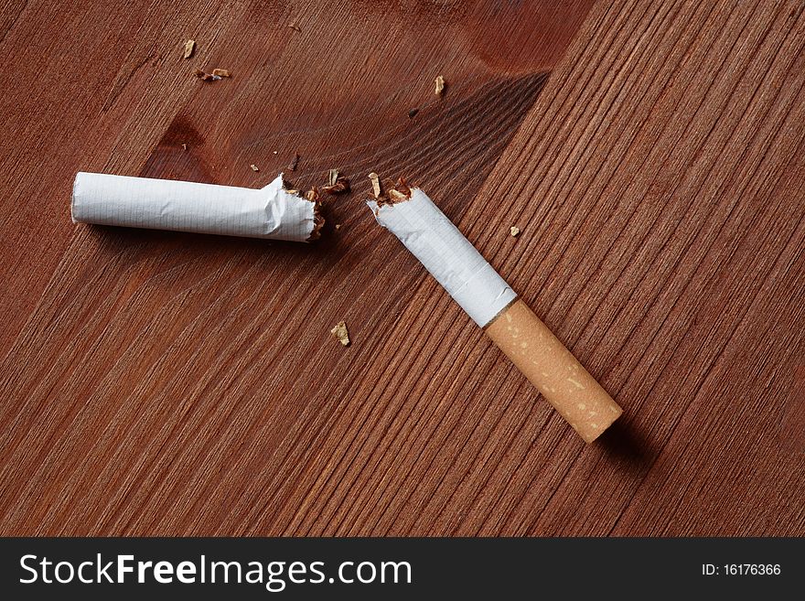 Broken cigarette closeup lying on wooden background. Broken cigarette closeup lying on wooden background