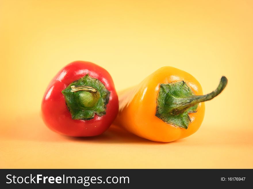 Hot red and yellow chili peppers on yellow background