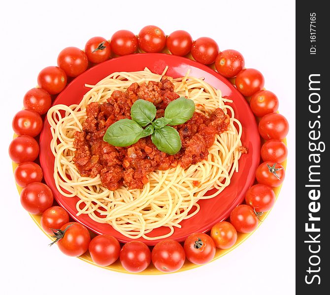 Spaghetti Bolognese on a plate decorated with fresh basil and surrounded with cherry tomatoes