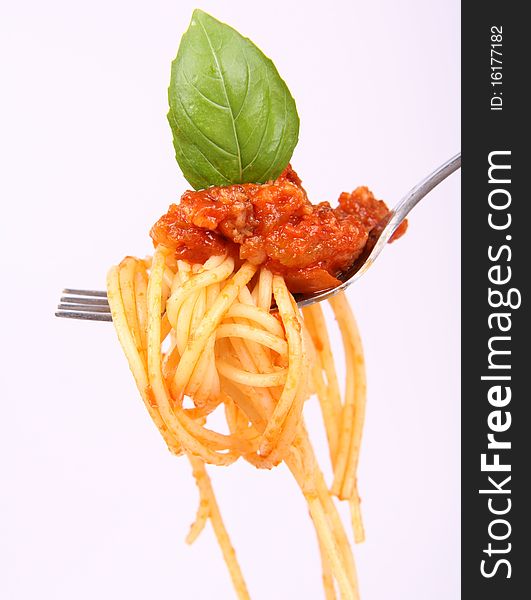 Spaghetti with sauce bolognese hanging on a fork decorated with fresh basil. Spaghetti with sauce bolognese hanging on a fork decorated with fresh basil