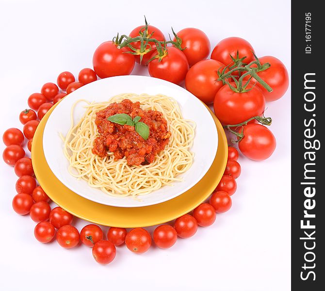 Spaghetti Bolognese on a plate decorated with fresh basil, some tomatoes and cherry tomatoes