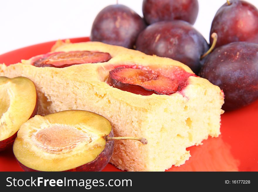 Portion of a Plum Pie and some fresh plums on a red plate