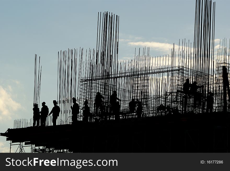 Silhouettes of builders and building structures on the background of a sunset. Silhouettes of builders and building structures on the background of a sunset
