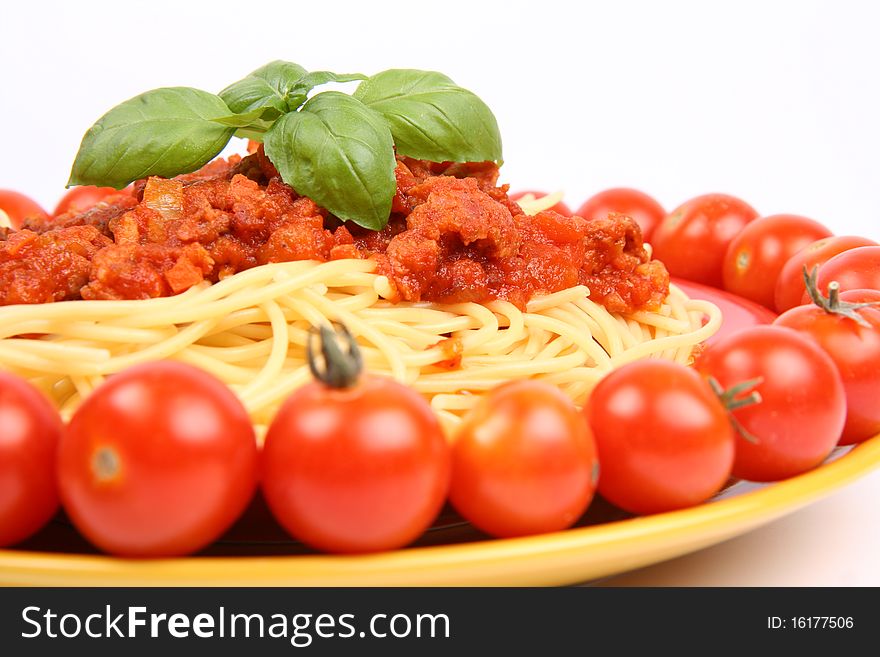 Spaghetti Bolognese on a plate decorated with fresh basil and cherry tomatoes around it