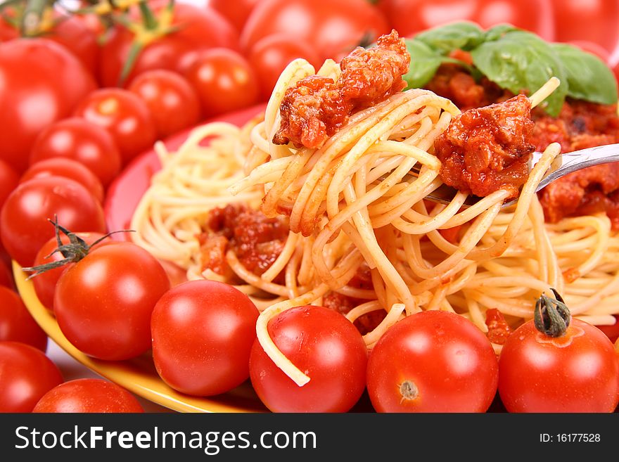 Spaghetti Bolognese on a plate decorated with fresh basil and surrounded with tomatoes and cherry tomatoes in close up