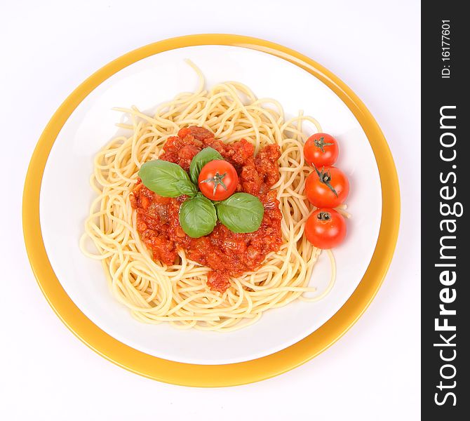 Spaghetti Bolognese on a plate decorated with fresh basil and cherry tomatoes on white background