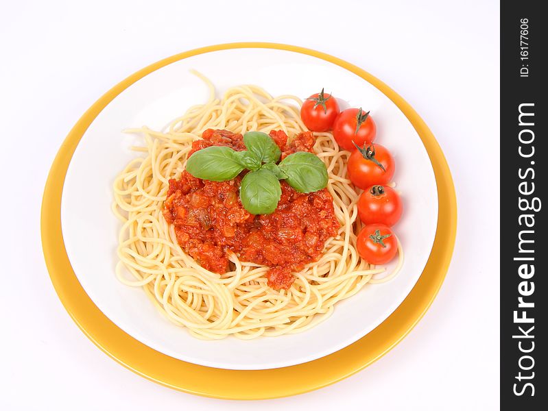 Spaghetti Bolognese on a plate decorated with fresh basil and cherry tomatoes on white background