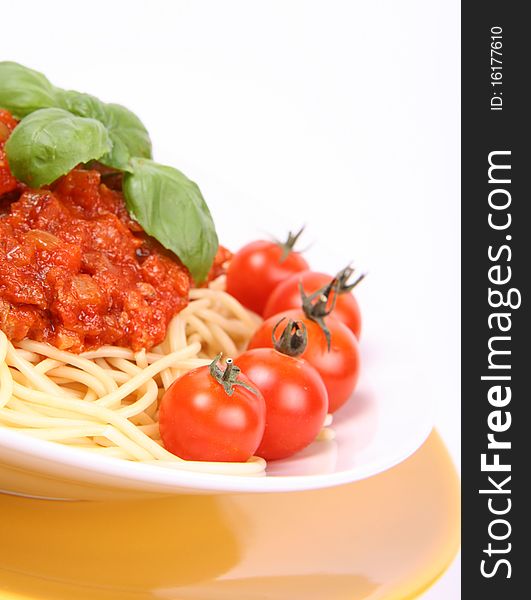 Spaghetti Bolognese on a plate decorated with fresh basil and cherry tomatoes in close up