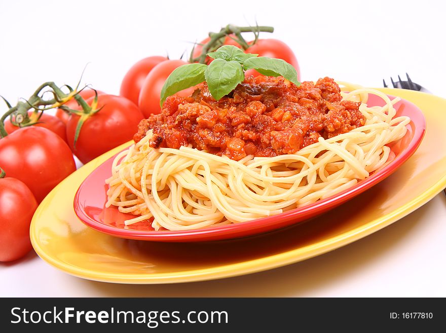 Spaghetti Bolognese on a plate decorated with fresh basil and some fresh tomatoes