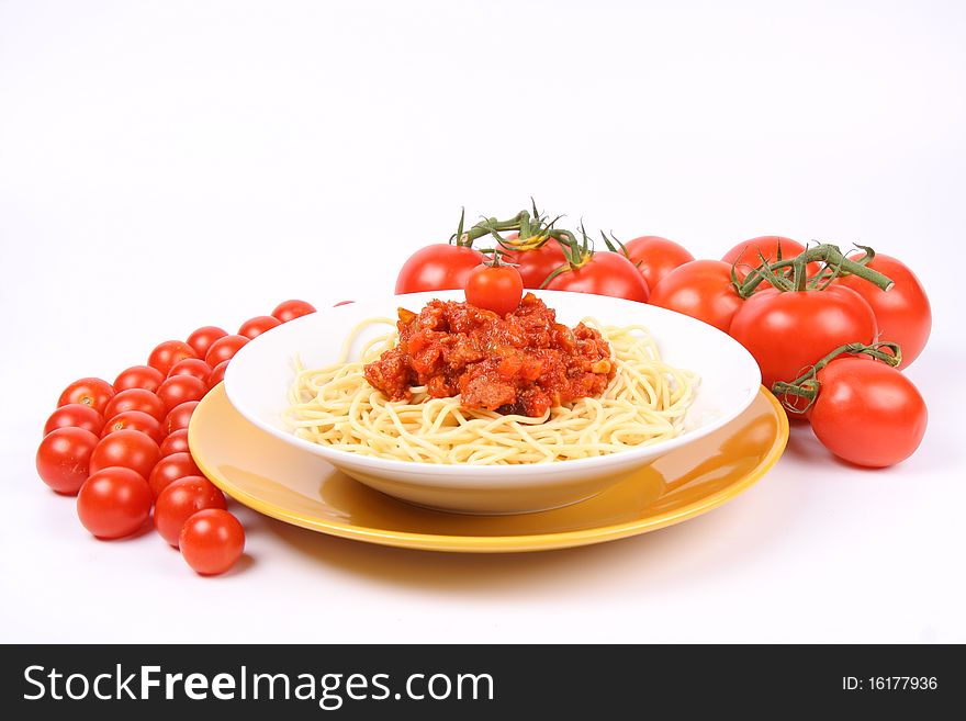 Spaghetti Bolognese on a plate decorated with fresh basil and surrounded with tomatoes and cherry tomatoes on white background