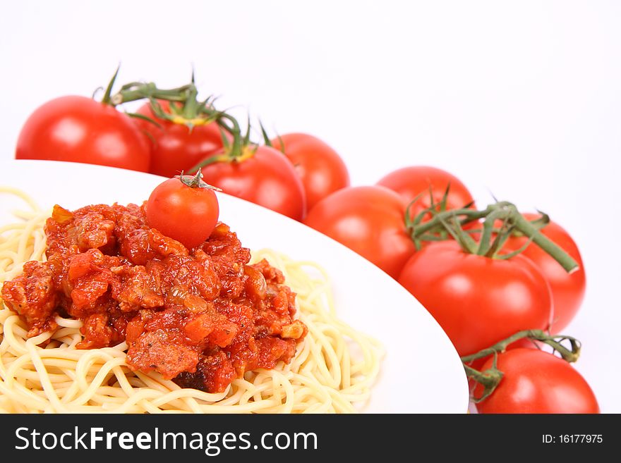 Spaghetti Bolognese on a plate surrounded with tomatoes and decorated cherry tomato