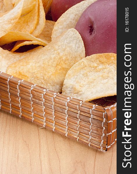 Potato chips with a potato on a wooden tray.