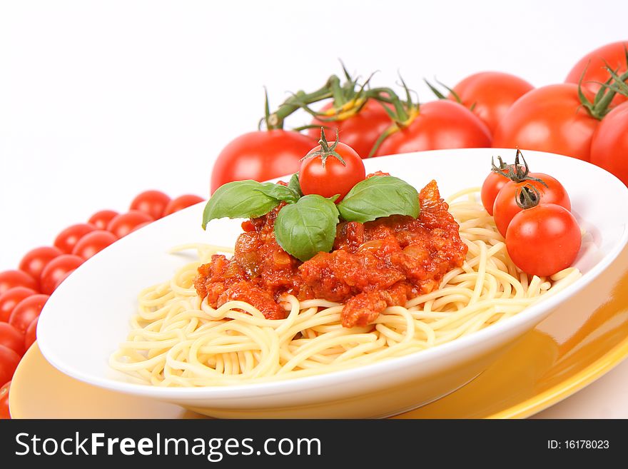 Spaghetti Bolognese on a plate decorated with fresh basil and cherry tomatoes surrounded with regular tomatoes