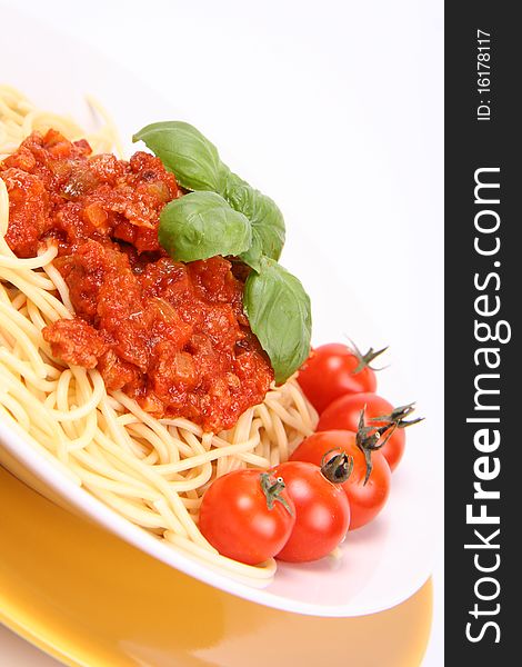 Spaghetti Bolognese on a plate decorated with fresh basil and cherry tomatoes in close up