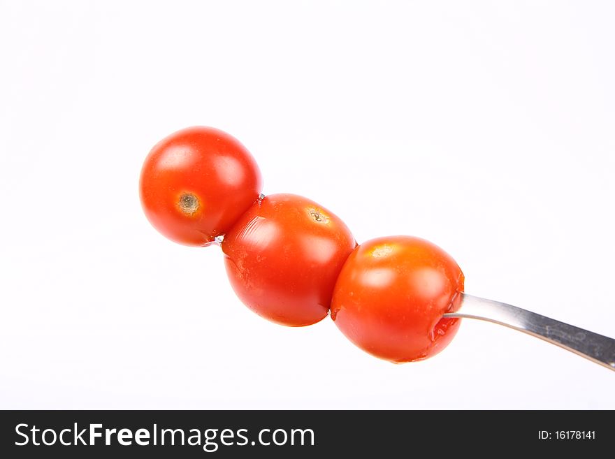 Cherry tomatoes on a fork on white background