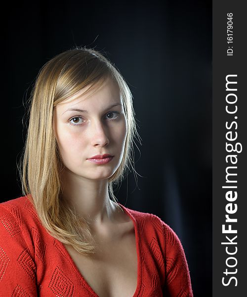 Portrait of young blonde girl in red on black background. Portrait of young blonde girl in red on black background