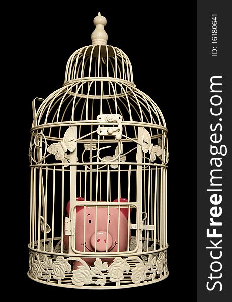 Piggy bank trapped in a bird cage isolated on black background. Piggy bank trapped in a bird cage isolated on black background