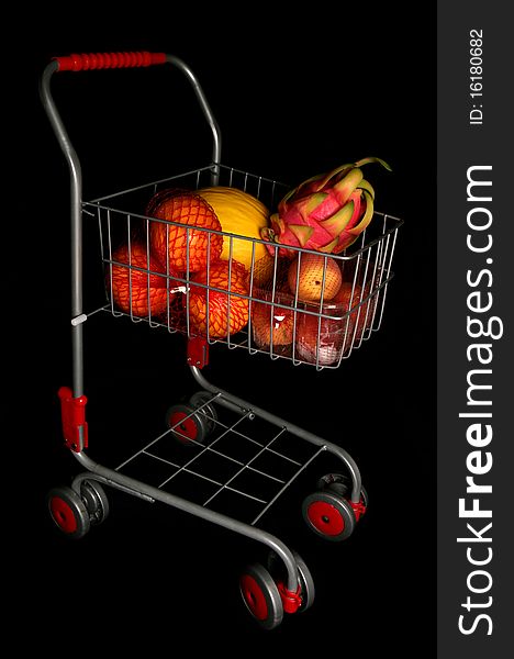 Shopping trolley full of fruit isolated on a black background