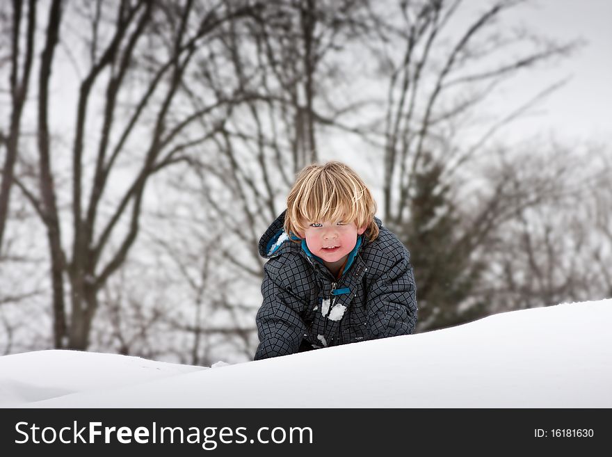 A little boy peaking over the top of a snowy mountain. A little boy peaking over the top of a snowy mountain.