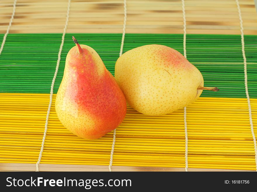 Two ripe pears on a straw napkin