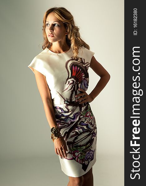 Young blond woman in elegant silk dress, studio shot