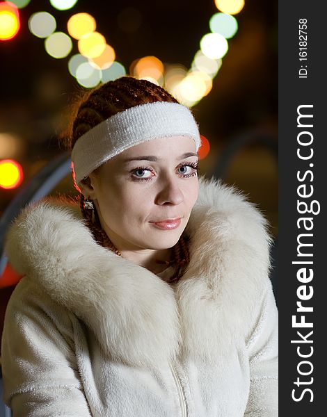 Portrait of a fashionable teenage girl in white fur coat outdoors at night. Portrait of a fashionable teenage girl in white fur coat outdoors at night