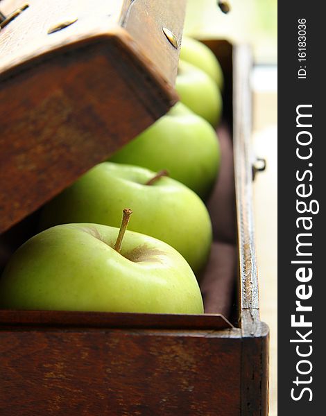 Green apples on the background of an old wooden chest