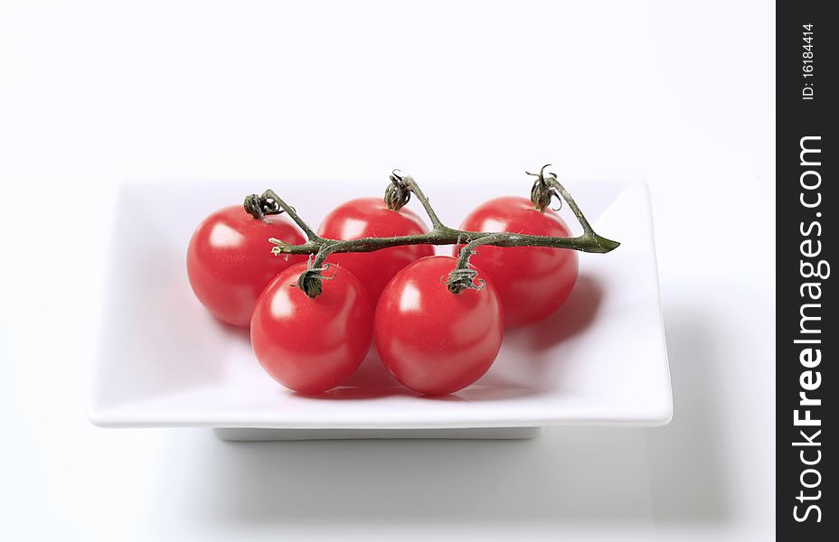 A bunch of fresh red tomatoes in a porcelain dish