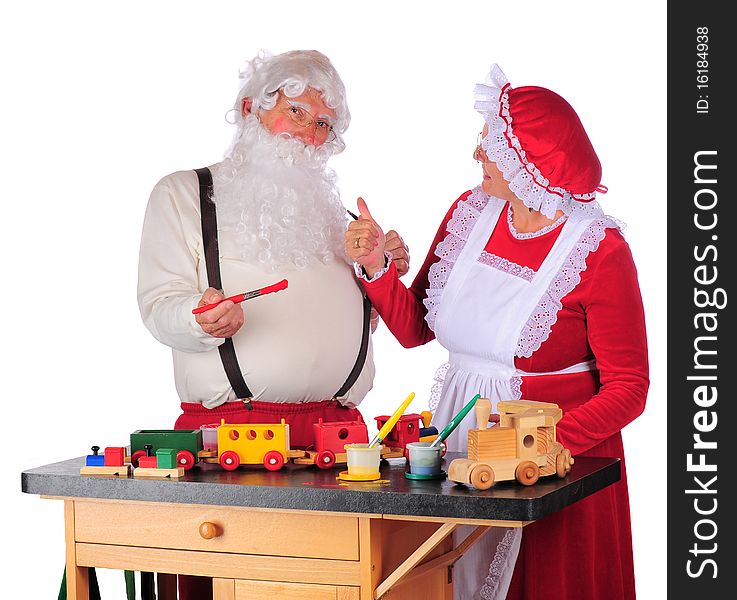 Mrs. Claus giving Santa a thumbs up as he paints toys for Christmas. Isolated on white. Mrs. Claus giving Santa a thumbs up as he paints toys for Christmas. Isolated on white.